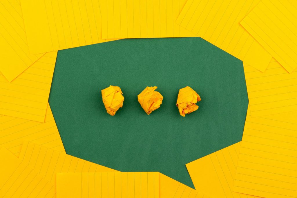 a green speech bubble with three dots inside on a yellow background